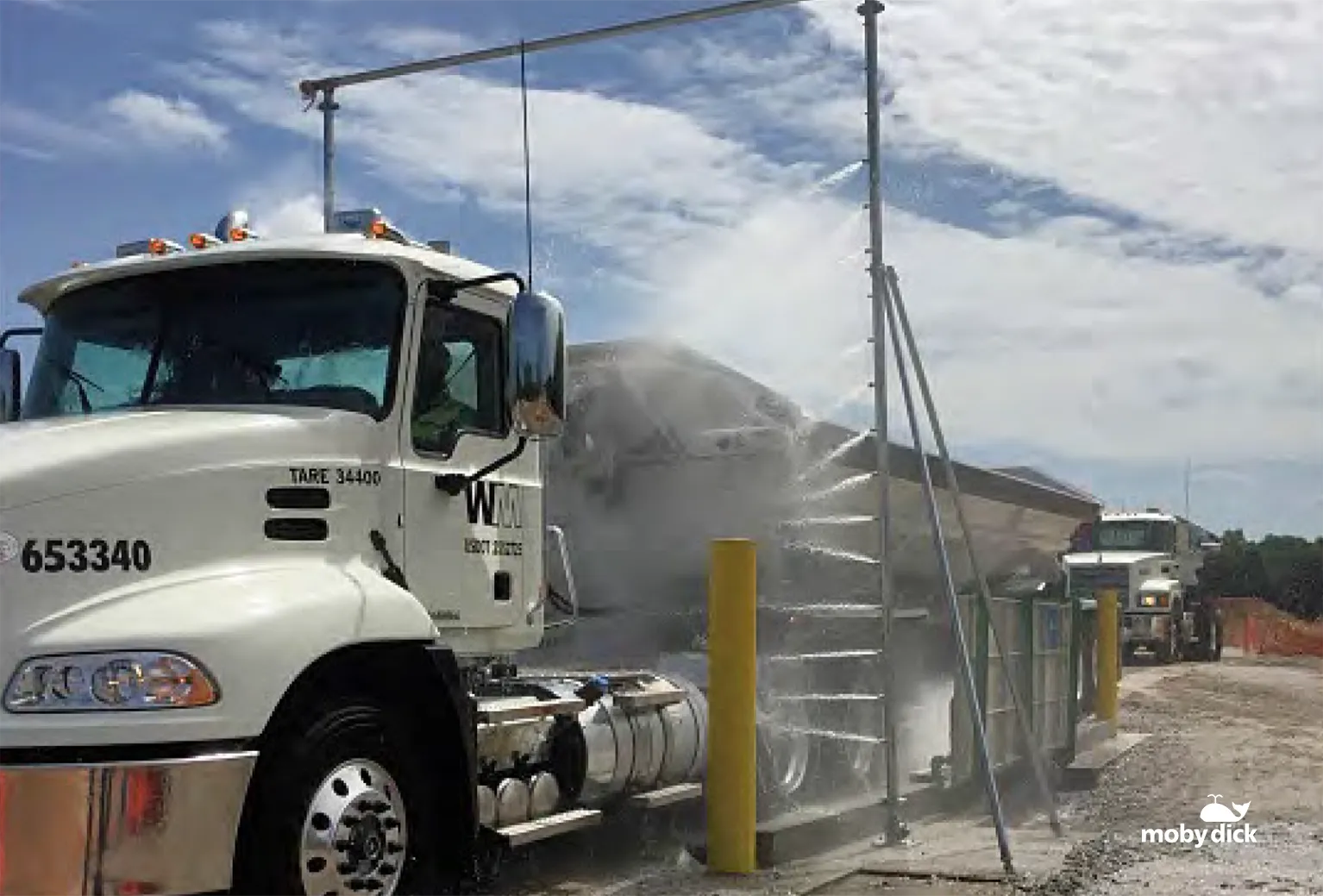 Truck passing through the automated demucking wash system with side spray bars at a coal mine site