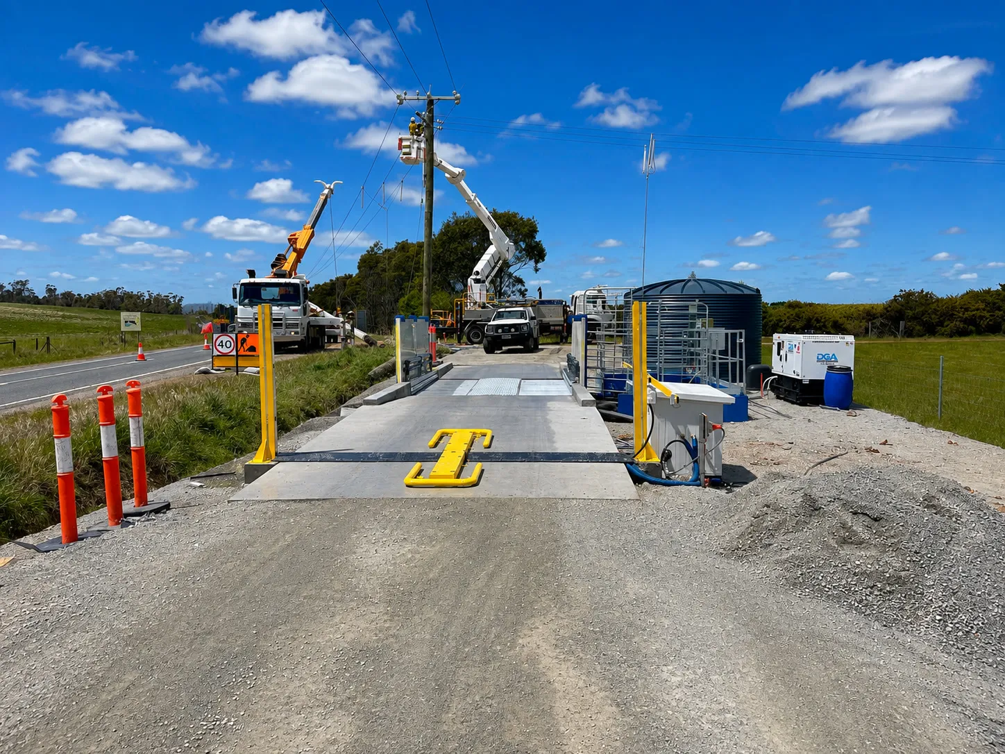 Vehicle disinfection gate with yellow spray posts being installed at a site entry