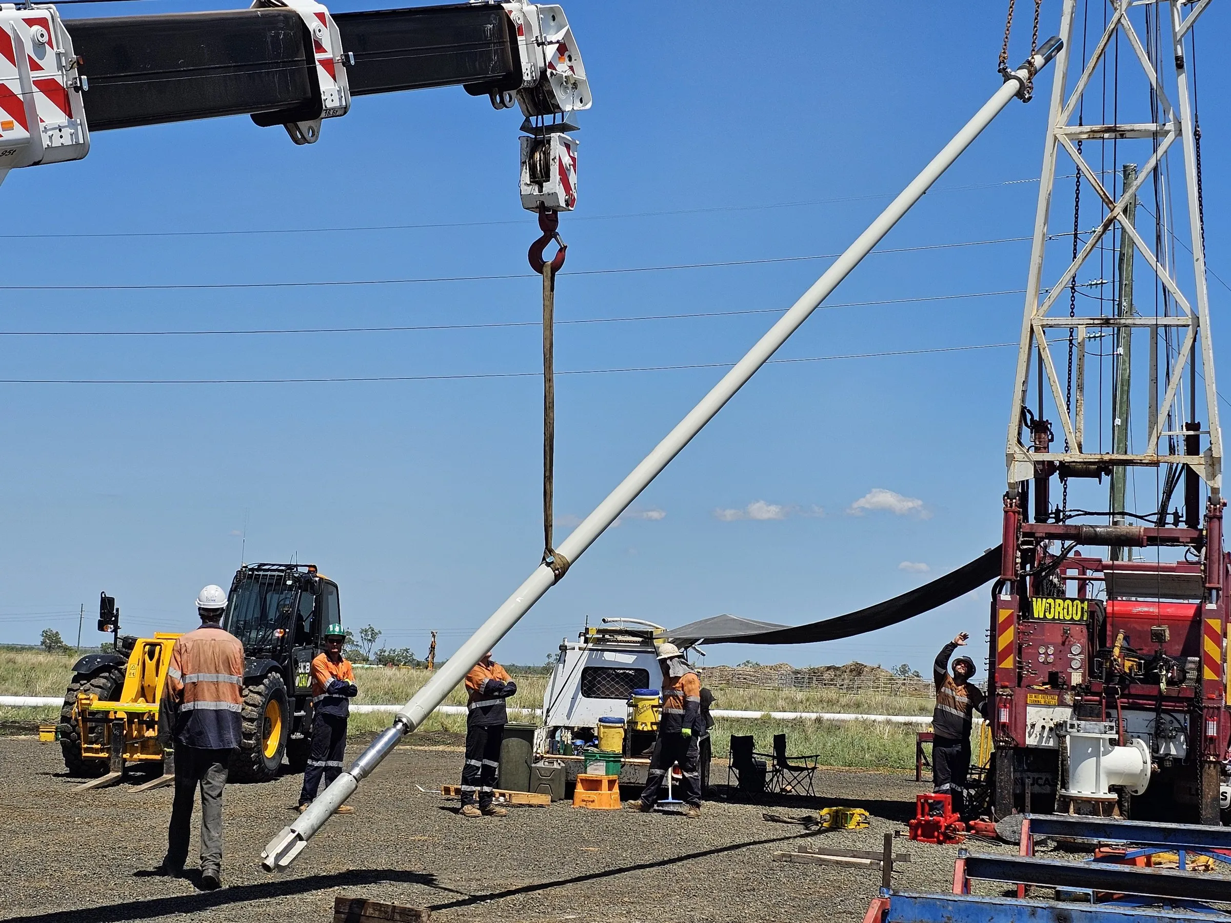 Submersible borehole pump assembly being lifted into a bore by crane on a mine site