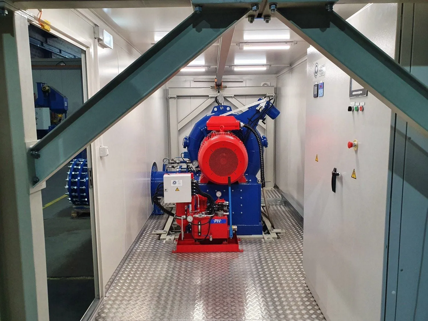 Blue Francis turbine and red generator inside the 20 ft container of a hydro power module, Victoria