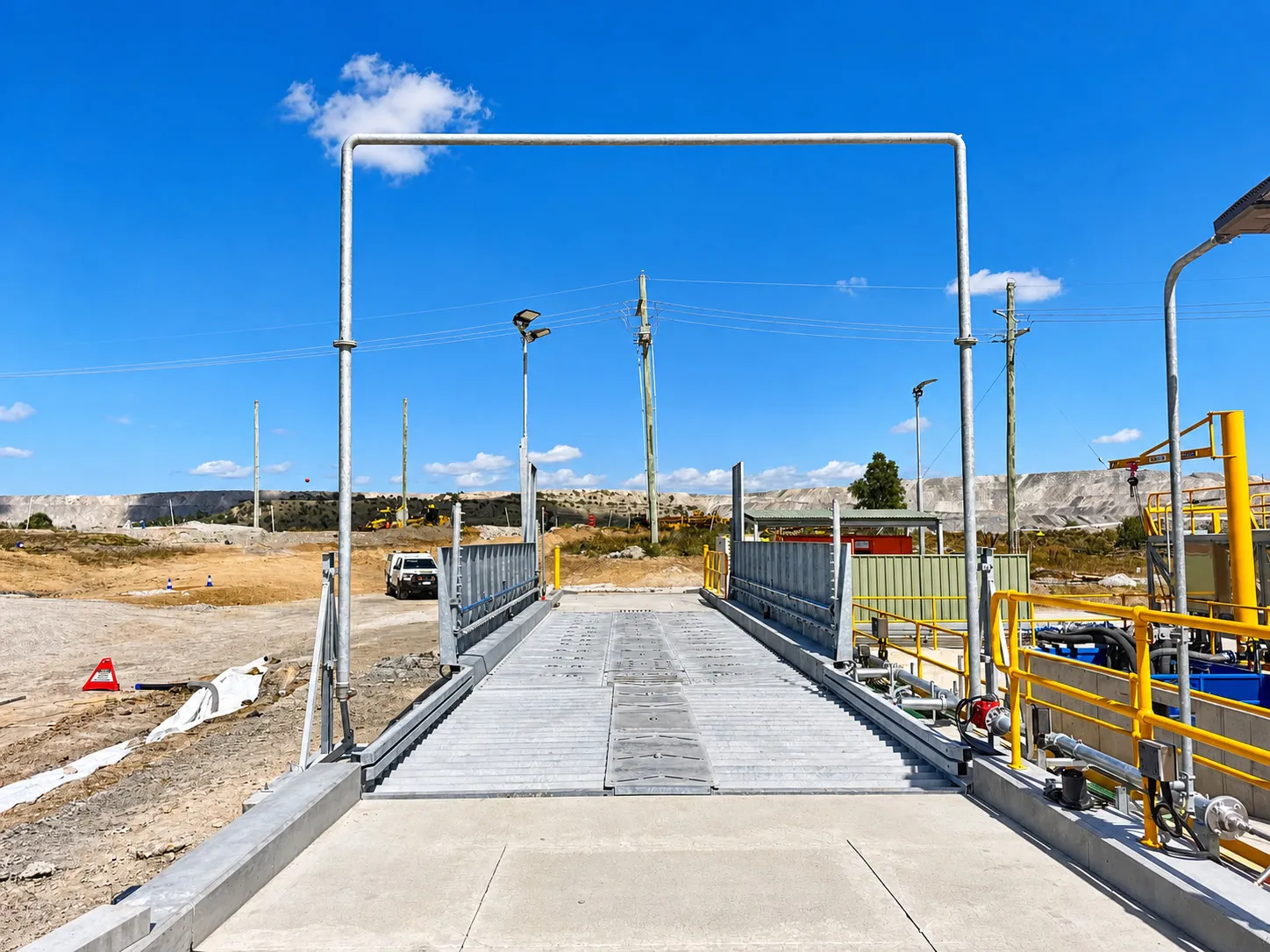 Drive-through vehicle wash bay with an overhead spray gantry over a concrete wash pad