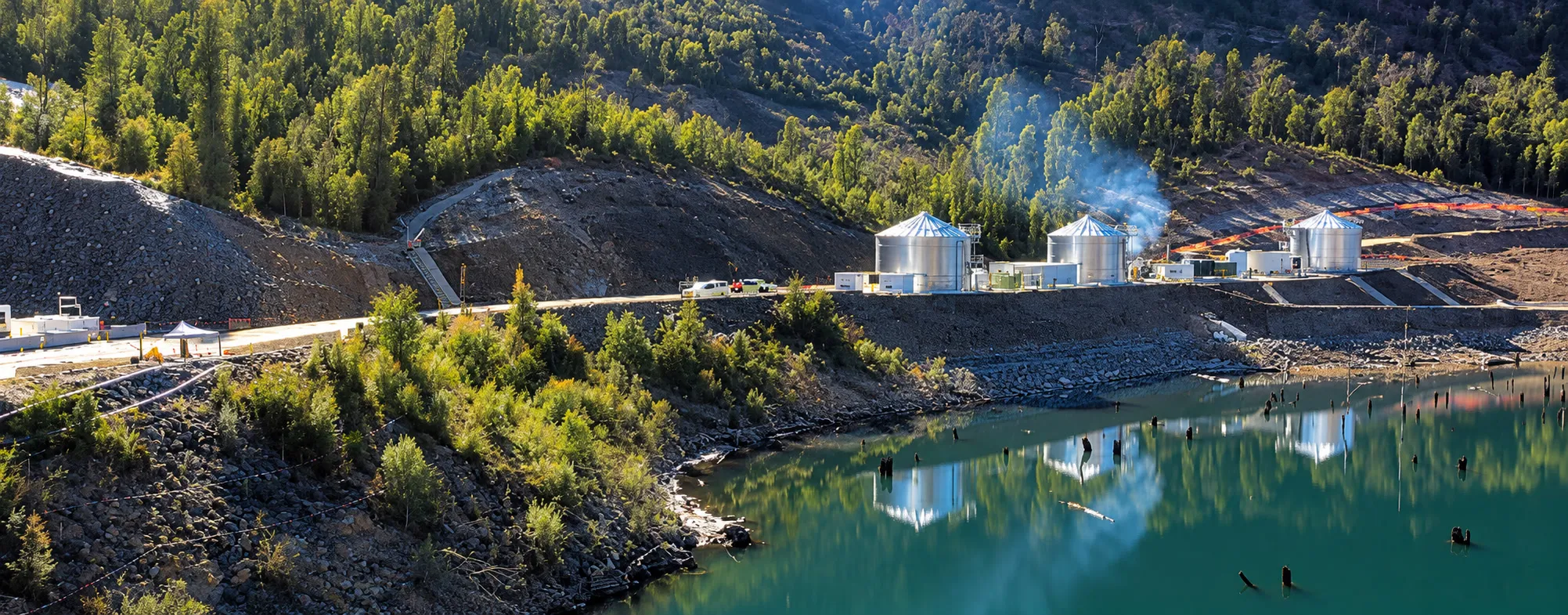 Water treatment tanks beside a reservoir in a forested valley